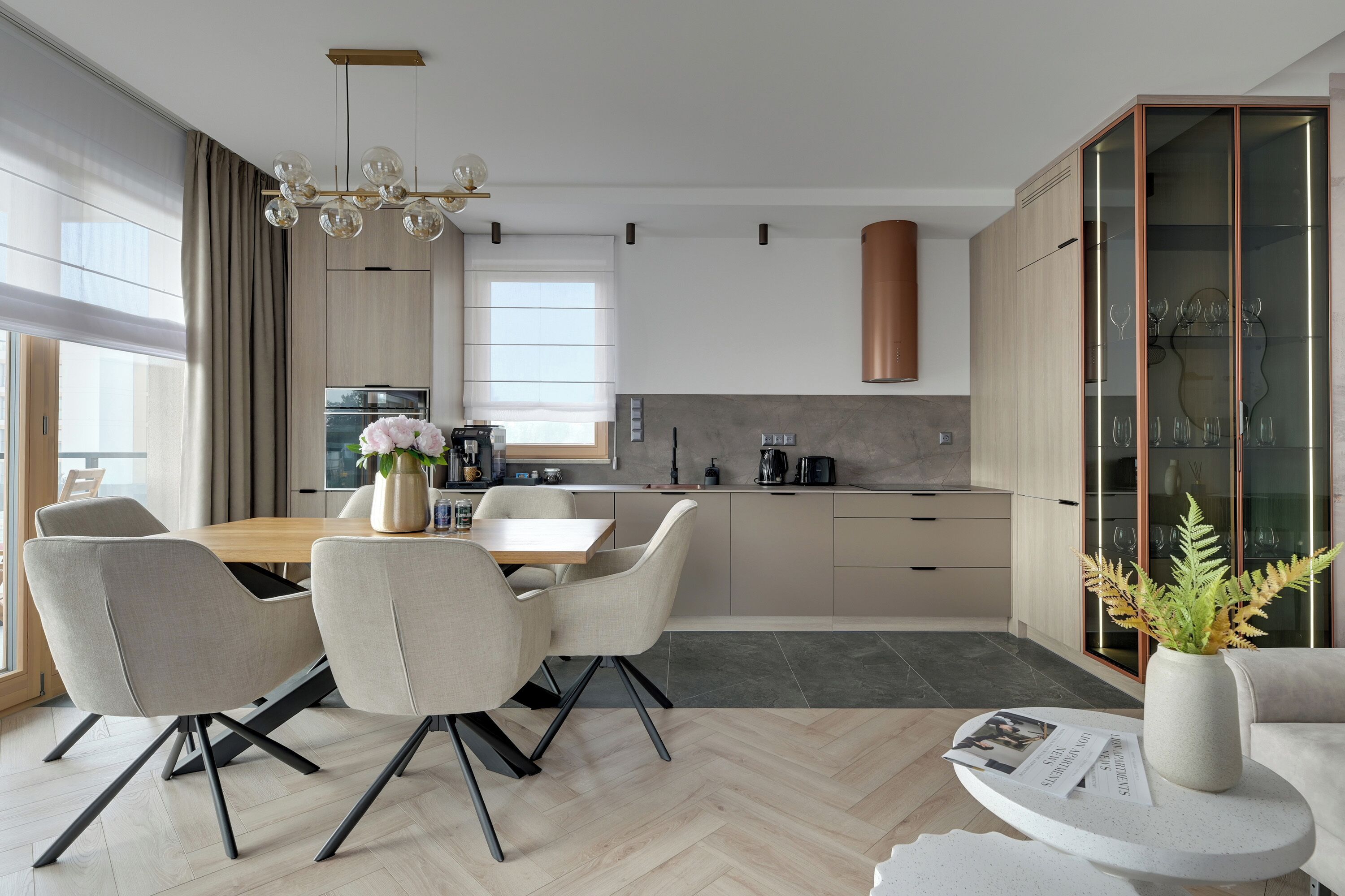 Una cocina moderna con comedor, que incluye una mesa de madera, sillas y una cafetera.