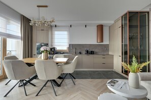 Cozinha moderna com área de jantar, incluindo uma mesa de madeira, cadeiras e uma máquina de café.