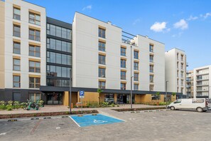 Un edificio moderno de varios pisos con estacionamiento, incluyendo un espacio reservado para personas con discapacidad.