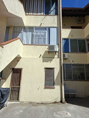 A multi-story building with external air conditioning units, a staircase, and barred windows. - Garden Apartment, just a short walk from the beach and equipped with every amenity (Italy)