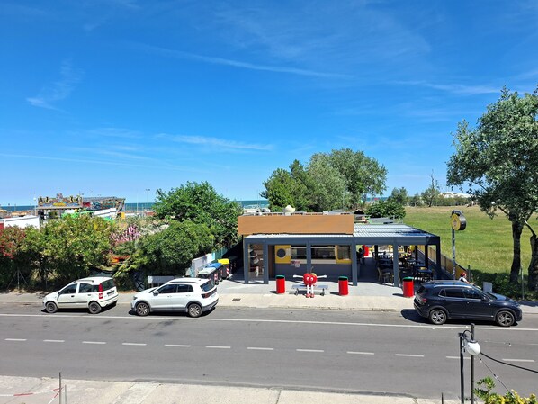 Une vue de rue avec un petit bâtiment, des voitures garées et un ciel bleu dégagé.