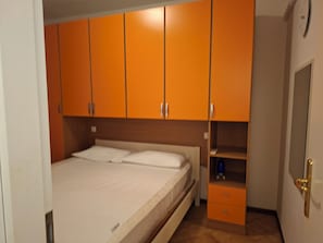 A bedroom with a single bed, a wardrobe, and a small shelf. - Garden Apartment, just a short walk from the beach and equipped with every amenity (Italy)