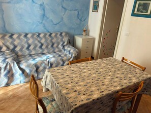Une pièce comprenant un canapé, une table avec des chaises, un meuble et une porte ornée d’un cadre.