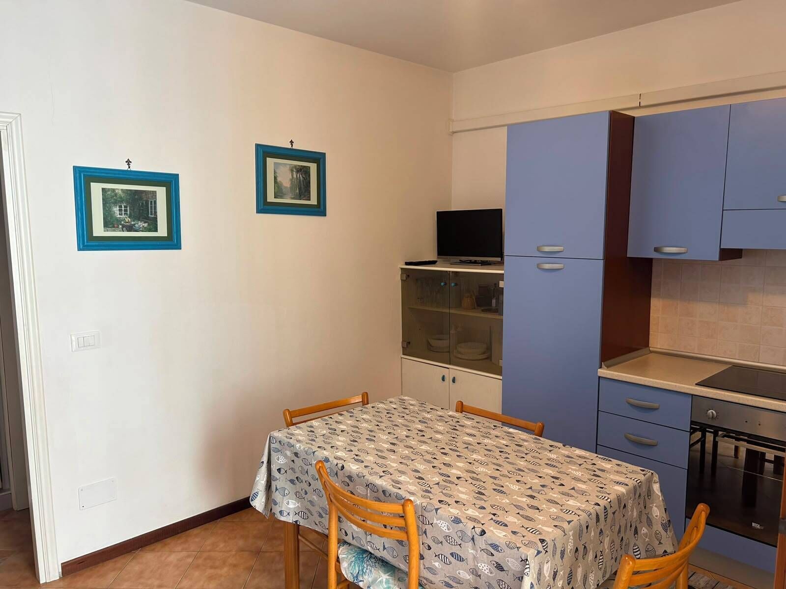 Een kleine keuken met een eettafel, stoelen en kastjes.