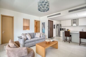 Ein modernes Wohnzimmer mit einem grauen Sofa, einem Holztisch und freiem Blick in den angrenzenden Küchenbereich.