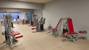 Ein Fitnessraum mit verschiedenen Trainingsgeräten, darunter Gewichtbänke und Kabelzugmaschinen.