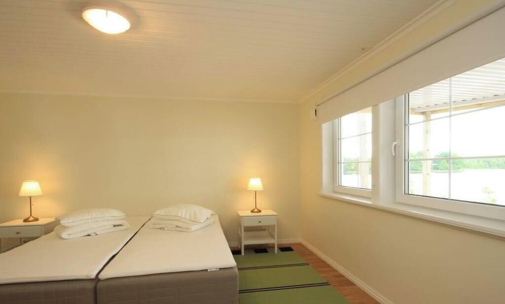 Une chambre avec un lit, deux tables de chevet, des lampes, une fenêtre et un tapis vert.