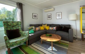 A living room with a sectional sofa, a patterned armchair, a coffee table, and a window with curtains. - 2 bedroom beautiful home in Kinnarumma (Kinnarumma)