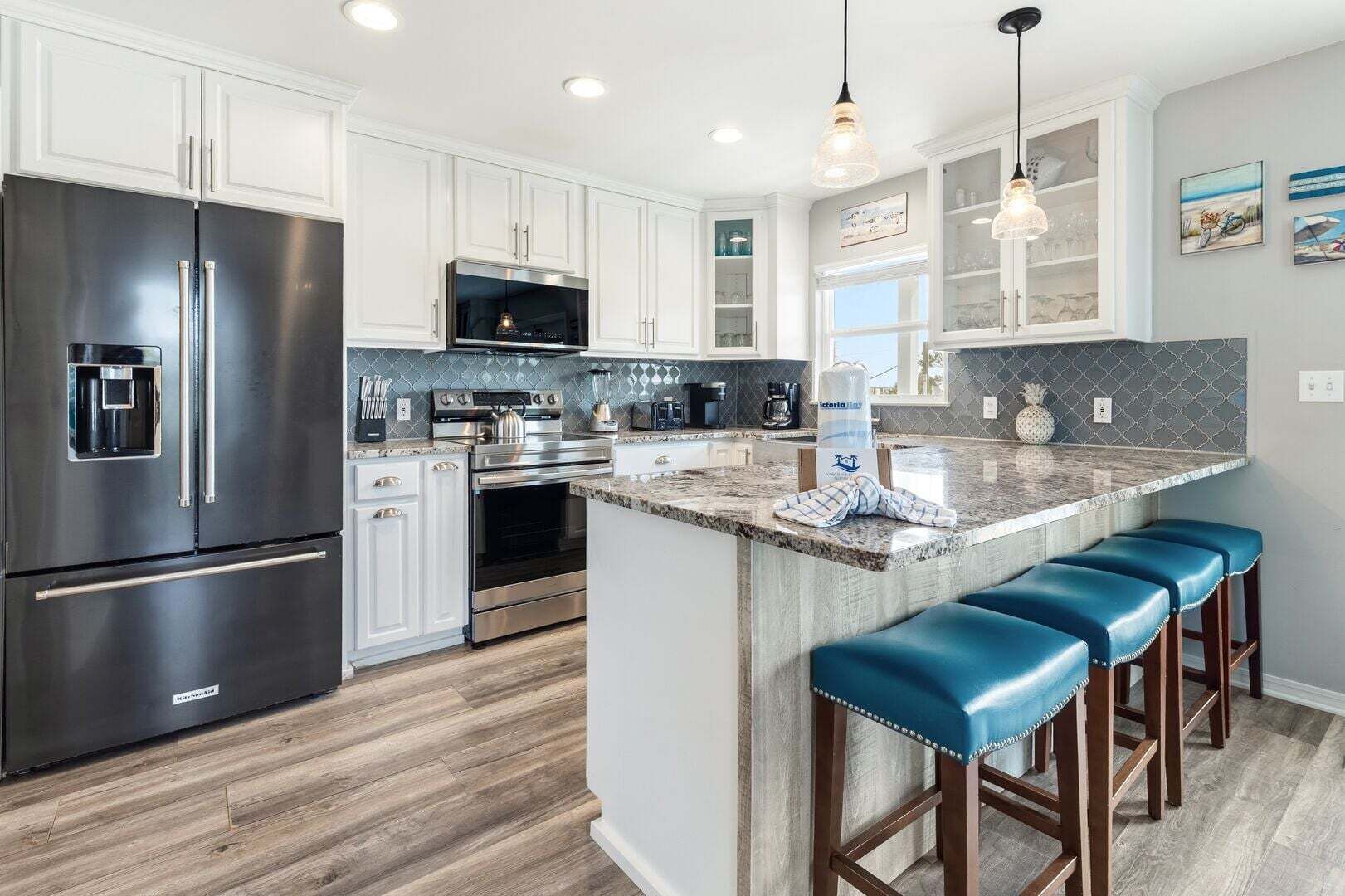 A modern kitchen with stainless steel appliances, a granite countertop, and bar stools.