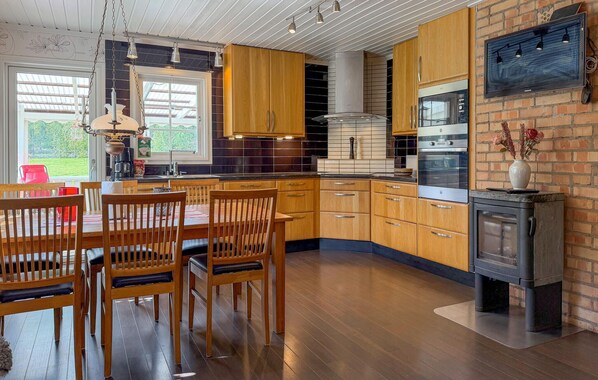 Une cuisine moderne avec des meubles en bois, des appareils électroménagers en acier inoxydable et un four encastré.
