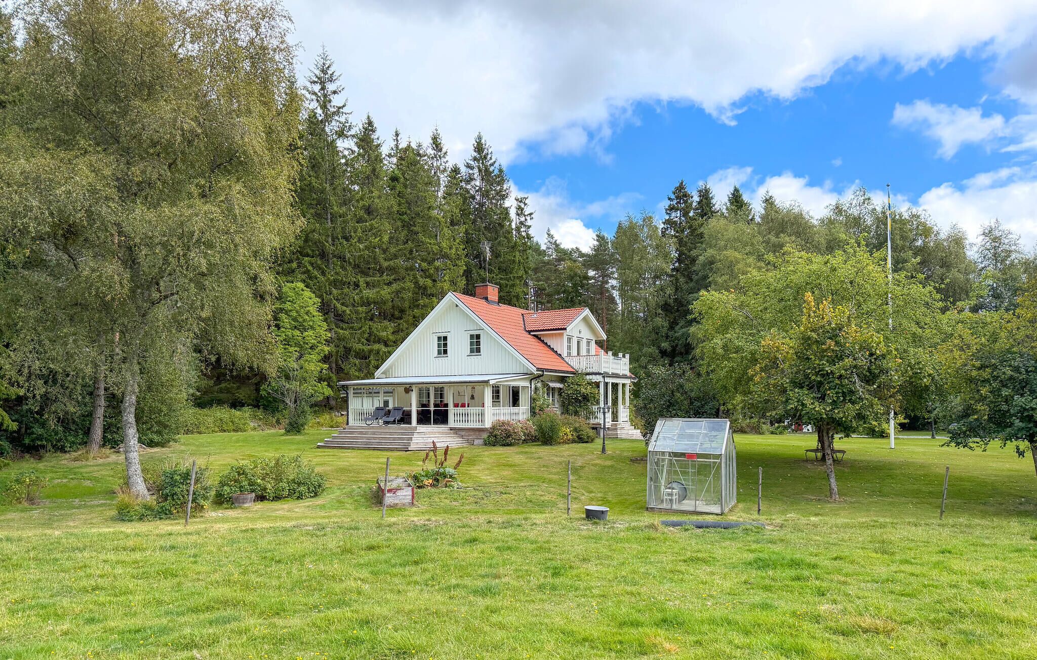 A white house with a red roof, surrounded by a grassy yard and trees.