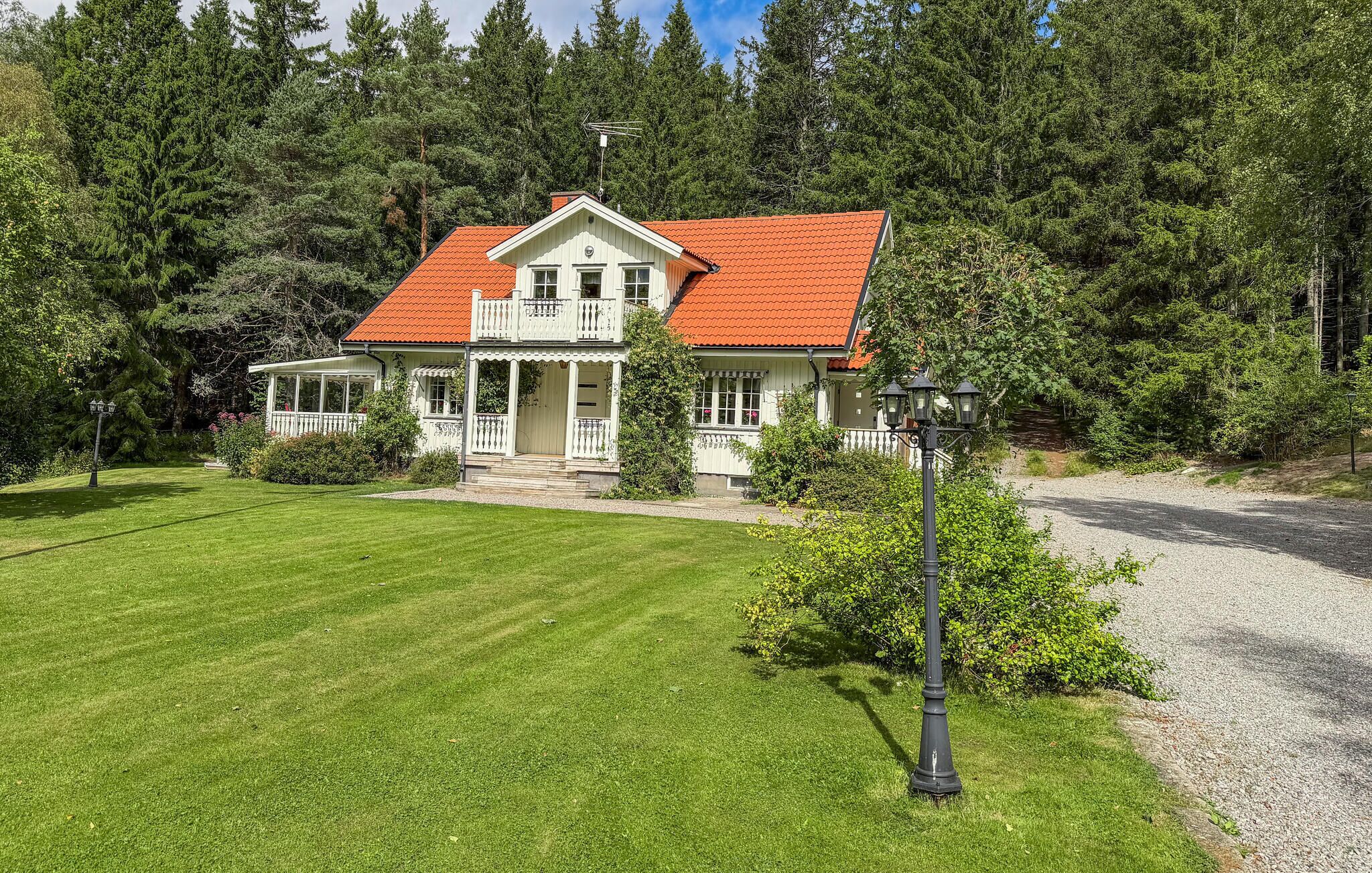 A two-story house with a red-tiled roof, a porch, and a well-maintained lawn.