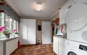 Eine Küche mit einer Bosch Waschmaschine, einem Feuerlöscher und einem Fenster mit Blumen.
