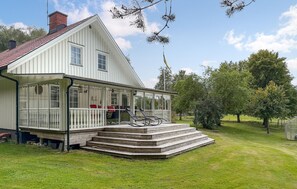 Ein weißes, zweistöckiges Haus mit einer überdachten Veranda und einer Treppe zum Eingang.
