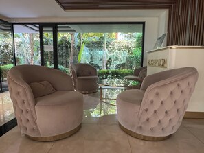 A reception area with a glass wall, two round armchairs, and a reception desk. - Qoople Cleopatra Exclusive - Cozy 1-bedroom apartment in Alanya (Alanya)