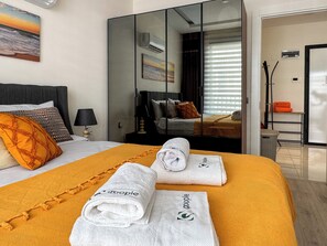 A hotel room with a bed, a large mirror, a painting, and a view of the outside. - Qoople Cleopatra Exclusive - Cozy 1-bedroom apartment in Alanya (Alanya)