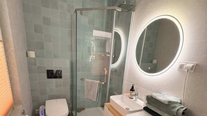 A modern bathroom with a glass shower enclosure, a toilet, a sink with a mirror, and a washing machine. - Spacious apartment in central Zielona Gora (Zielona Góra)