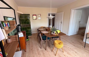 Uma sala de jantar com mesa de madeira, cadeiras, luminária pendente e painel de azulejos verdes.