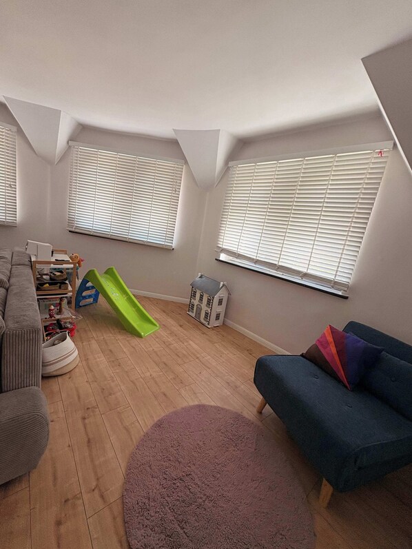 Una sala de estar con un tobogán verde, un sofá azul y una pequeña maqueta de una casa.