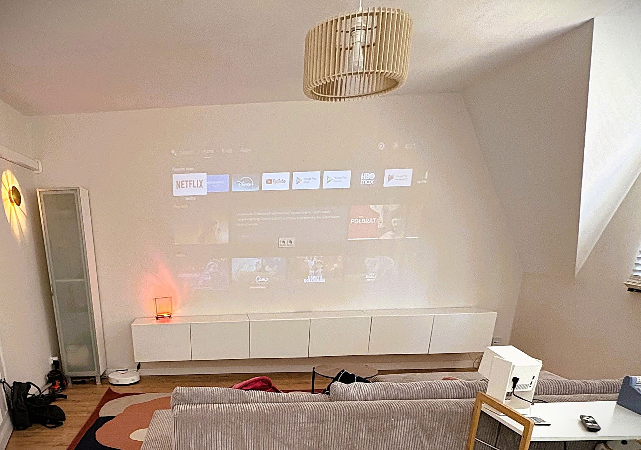 A living room with a white sofa, a coffee table, and a TV wall displaying various streaming services.