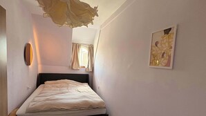 A bedroom with a bed, a round rug, a wall-mounted light, and a framed picture. - Spacious apartment in central Zielona Gora (Zielona Góra)