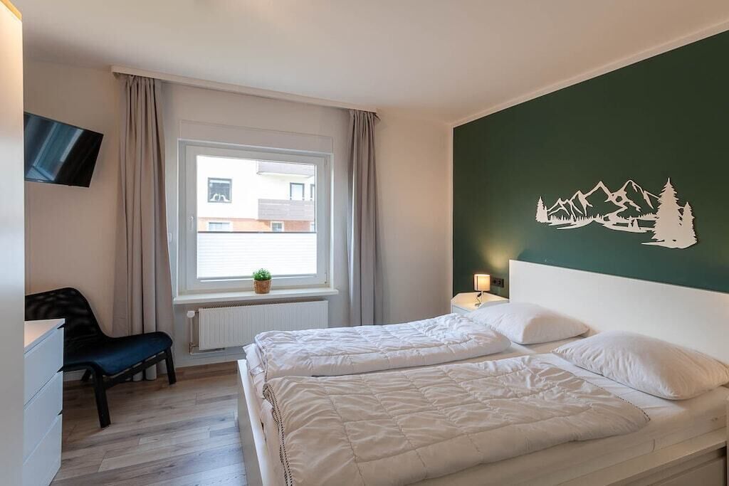 A hotel room with two beds, a TV, a window with curtains, and a wall decal.