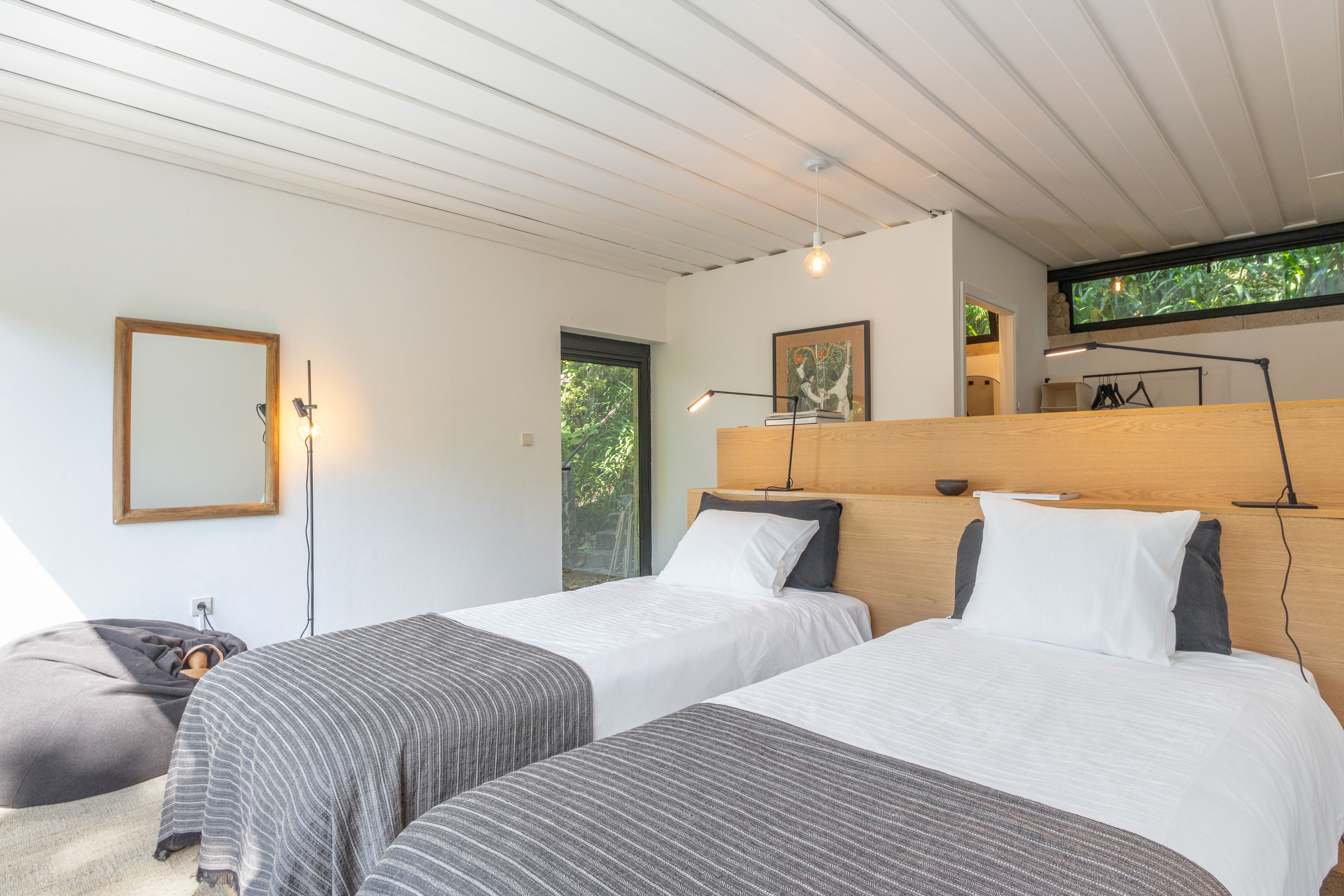 Una camera da letto moderna con due letti, un grande specchio e una televisione a parete.