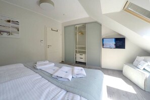 Ein Hotelzimmer mit Bett, Sitzgelegenheit, Kleiderschrank und Fernseher.