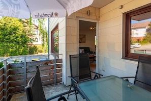 An outdoor seating area with a table and chairs, a wooden fence, and a building entrance. - Mountain view with balcony (Braunlage)