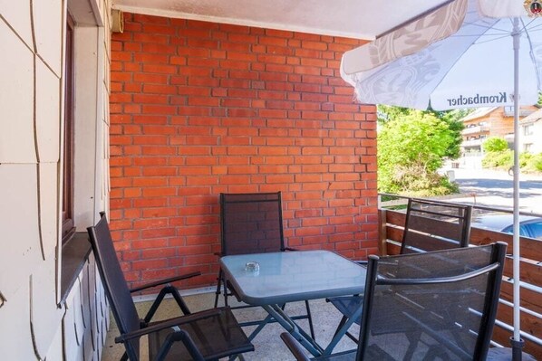 A small outdoor seating area with a brick wall, a table, and two chairs. - Mountain view with balcony (Braunlage)