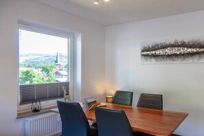 A conference room with a large window, a table, and four chairs. - Mountain view with balcony (Braunlage)