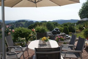 Una terrazza esterna con un tavolo rotondo, sedie e un ombrellone.