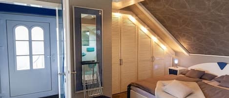 Un dormitorio con cama, una silla, un armario y una puerta.