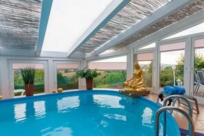 Una piscina interna con una statua dorata, porte in vetro e piante in vaso.