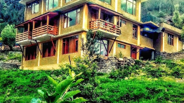 Un immeuble à plusieurs étages doté de balcons, entouré de verdure.