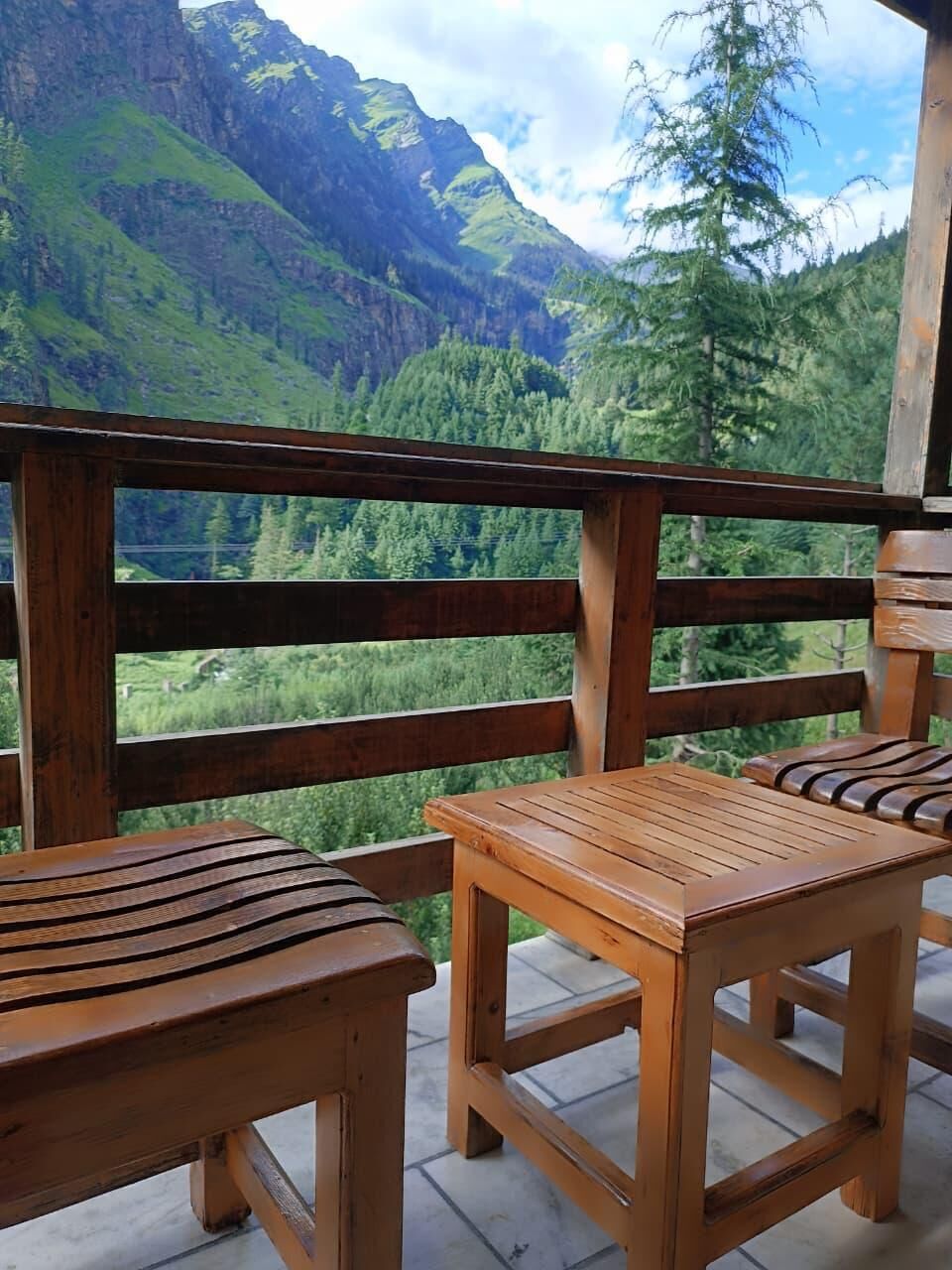 Un pontile in legno con due tavoli e sedie, affacciato su un paesaggio montuoso.