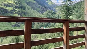 Un balcón de madera con vista a un paisaje montañoso.
