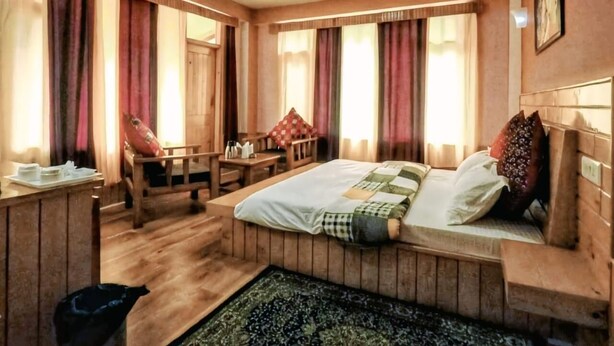Una habitación con una cama, un escritorio de madera y una silla.