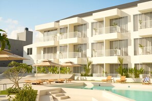 Un hotel con varios balcones, piscina y zonas de estar al aire libre.