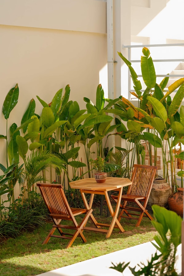 An outdoor seating area with a wooden table and chairs, surrounded by lush tropical plants. - O.Serendipity Kuta (Kuta)
