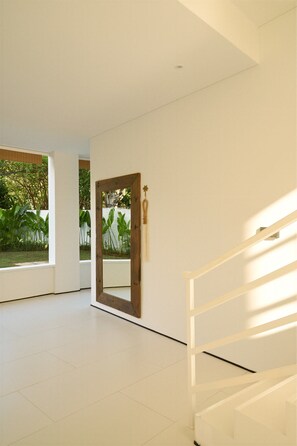 A spacious room with a large mirror, a wooden door, and a staircase. - O.Serendipity Kuta (Kuta)