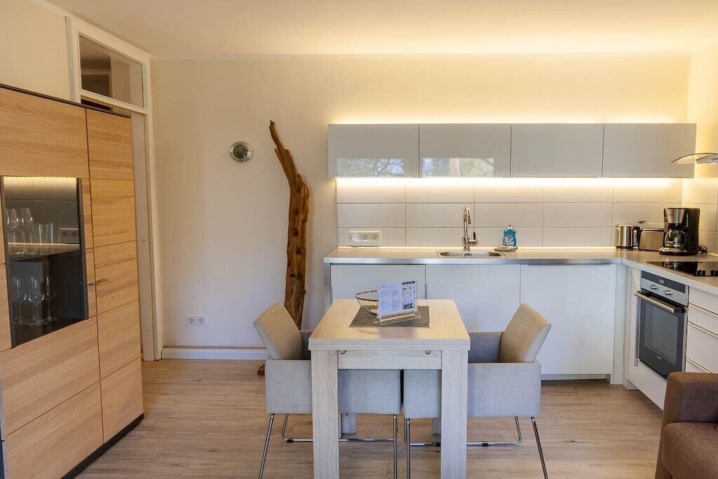 Eine moderne Küche mit Essbereich, Holzschränken und einem eingebauten Backofen.