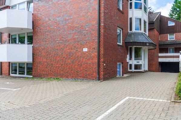 A multi-story residential building with a brick facade, a gated driveway, and a small entrance with a door. - Wurmberg destination with balcony (Braunlage)