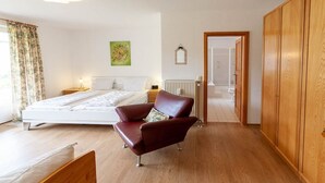 Una camera da letto con un letto, una sedia rossa, un armadio in legno e un termosifone.