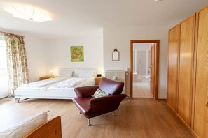 A bedroom with a bed, a red chair, wooden wardrobe, and a radiator. - Holiday apartment with 2 bedrooms (Braunlage)