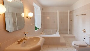Un bagno con una vasca da bagno ampia, una doccia separata e un WC.