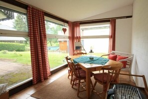 A dining area with a table and chairs, a view of the garden, and a heart-shaped decoration on the wall. - Holiday apartment with 2 bedrooms (Braunlage)