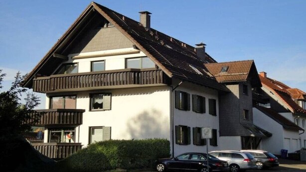 Un edificio a due piani con tetto spiovente, numerose finestre e un balcone.