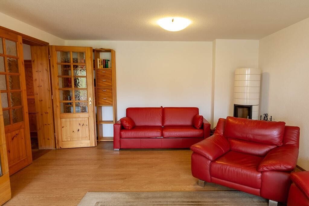 Un salon avec un canapé en cuir rouge, des meubles en bois et un mur blanc.