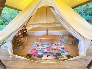 A tent with a quilted floor mat, a wooden table, and a hammock. - Rainbowforest (ishigaki)